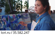 A woman paint artist drawing a colorful painting on a canvas - looking on the side for reference. Стоковое видео, видеограф Константин Шишкин / Фотобанк Лори