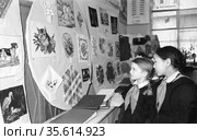 Выставка детского творчества проходит в школе номер девять, вышивка сделанная ученицами развешена на стенах одного из учебных помещений, две девочки в школьной форме стоят рядом, Якутск, июнь 1959. Редакционное фото, фотограф Варфоломей Тетерин / Фотобанк Лори