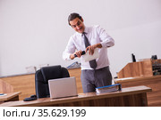 Young male employee stapling paper in the office. Стоковое фото, фотограф Elnur / Фотобанк Лори