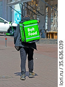Пеший курьер службы Bolt Food с зеленой термосумкой на улице Киева, Украина (2021 год). Редакционное фото, фотограф FMRU / Фотобанк Лори