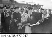 Торжественные мероприятия в честь лётчика на аэродроме, пилот самолета жмёт руку своему товарищу, большое количество детей и взрослых позади них, Якутия, 1960 год. Редакционное фото, фотограф Варфоломей Тетерин / Фотобанк Лори
