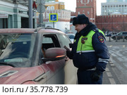 Инспектор дорожно-патрульной службы полиции проверяет документы водителя остановленного автомобиля (2017 год). Редакционное фото, фотограф Free Wind / Фотобанк Лори