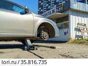 Приподнятый автомобиль на домкрате без колеса в шиномонтаже на улице (2021 год). Стоковое фото, фотограф Sergei Gorin / Фотобанк Лори