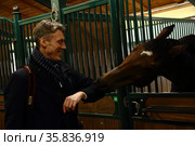 Лошадь в вольере кусает локоть мужчины (2021 год). Редакционное фото, фотограф Дмитрий Неумоин / Фотобанк Лори