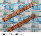 Слова "бюрократия", "коррупция", сложенные из деревянных кубиков с буквами на фоне из российских денежных купюр. Стоковое фото, фотограф Цибаев Алексей / Фотобанк Лори