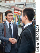 Two young businessman handshaking in houhai, Beijing, China. Стоковое фото, агентство Ingram Publishing / Фотобанк Лори