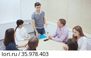 Friendly lawyer sitting with laptop in informal office meeting space, consulting his young female clients. Стоковое видео, видеограф Яков Филимонов / Фотобанк Лори