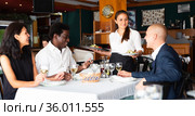 smiling female waiter bringing order to group of friens in restaurante. Стоковое фото, фотограф Яков Филимонов / Фотобанк Лори