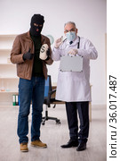 Masked man burglar bribing old doctor for getting vaccine. Стоковое фото, фотограф Elnur / Фотобанк Лори