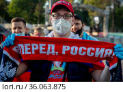 Российский футбольный болельщик в защитной респираторе и перчатках на территории фан-зоны на стадионе "Лужники" перед началом трансляции матча чемпионата Европы по футболу Евро-2020 между командами Бельгии и России (2021 год). Редакционное фото, фотограф Николай Винокуров / Фотобанк Лори