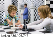 Boy adn girl solving puzzle together in room stylized like chessboard. Стоковое фото, фотограф Яков Филимонов / Фотобанк Лори