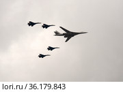 Группа истребителей СУ-35С и сверхзвуковой стратегический бомбардировщик дальней авиации Ту-160 во время парада пролетают над Красной площадью Москвы (2021 год). Редакционное фото, фотограф Free Wind / Фотобанк Лори