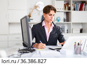 Focused attractive young man working with laptop and documents. Стоковое фото, фотограф Яков Филимонов / Фотобанк Лори