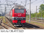 Российский пассажирский  электровоз ЭП2К-035 с пассажирским поездом крупным планом солнечным майским днем (2021 год). Редакционное фото, фотограф Виктор Карасев / Фотобанк Лори