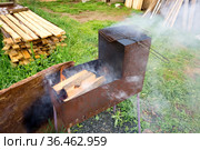 Железный самодельный мангал с горящими дровами на дачной лужайке летним днём. Стоковое фото, фотограф Светлана Попова / Фотобанк Лори