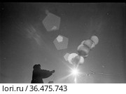 Сотрудник полярной научной станции стоит под открытым небом и запускает зонд в исследовательских целях, запуск метеозонд а для изучения атмосферы, село Уэлен, Чукотка, 1970. Редакционное фото, фотограф Варфоломей Тетерин / Фотобанк Лори