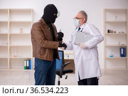 Masked man burglar bribing old doctor for getting vaccine. Стоковое фото, фотограф Elnur / Фотобанк Лори