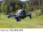 Moscow, 31 MAY 2021 : A new DJI FPV drone is flying during a sunny day on grass in beckground. Top Front View. Headless Quadcopter with Digital 4K 60 fps Hasselblad Camera and Remote Control. Стоковое фото, фотограф Алексей Ширманов / Фотобанк Лори