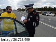 Инспектор дорожно-патрульной службы полиции проверяет документы водителя остановленного автомобиля (2021 год). Редакционное фото, фотограф Free Wind / Фотобанк Лори