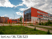 Современное здание общеобразовательной средней школы за забором в жилом микрорайоне летом. Красноярск. (2021 год). Стоковое фото, фотограф Светлана Попова / Фотобанк Лори