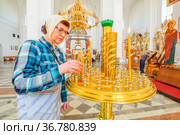 an elderly woman to put a candle in a candlestick in a church for a commemoration (2021 год). Редакционное фото, фотограф Акиньшин Владимир / Фотобанк Лори