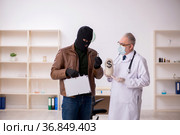 Masked man burglar bribing old doctor for getting vaccine. Стоковое фото, фотограф Elnur / Фотобанк Лори