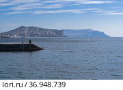 Одинокий рыбак ловит рыбу с буны. Курортный город Судак, Крым, солнечный день в октябре. (2021 год). Стоковое фото, фотограф Сергей Рыбин / Фотобанк Лори