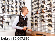 Interested man choosing hunting revolver in gun shop. Стоковое фото, фотограф Яков Филимонов / Фотобанк Лори
