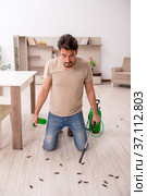 Young man exterminating cockroaches at home. Стоковое фото, фотограф Elnur / Фотобанк Лори