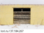 The facade of a small yellow one-story building, the entrance of which is closed with boards. Стоковое фото, фотограф Александр Клёнов / Фотобанк Лори