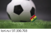 Ghana flag on the football field. Soccer championship. Football classic black and white ball rolls in the background. Sports Competition. The national flag of the country. Green fresh lawn grass. Стоковое видео, видеограф Ирина Ткачук / Фотобанк Лори