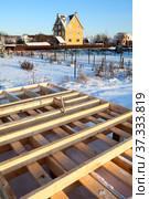 Wood frame house subfloor on pile foundation, real estate under construction against brick house at winter season, Russia. Стоковое фото, фотограф Кекяляйнен Андрей / Фотобанк Лори
