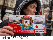 Женщина держит открытку с поздравлением с Днем советской армии на акции коммунистов на площади Революции в центре города Москвы, Россия (2022 год). Редакционное фото, фотограф Николай Винокуров / Фотобанк Лори