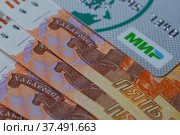 Пластиковая карта Мир на фоне Российских денег.Карта мир на пятитысячных купюрах. (2022 год). Редакционное фото, фотограф Гребенев Пётр / Фотобанк Лори
