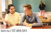 Intelligent asian teen girl explaining study material to her classmate in schoolroom. Стоковое видео, видеограф Яков Филимонов / Фотобанк Лори