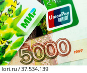 Карты "Мир" и UnionPay на фоне пятитысячной купюры (2022 год). Редакционное фото, фотограф SevenOne / Фотобанк Лори