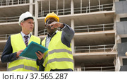 Two successful architects standing on the construction site are discussing the construction plan, holding drawings in their hands. Стоковое видео, видеограф Яков Филимонов / Фотобанк Лори