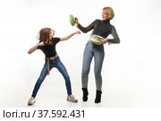Мама и дочка веселятся используя кухонную посуду, девочка нападает, мама обороняется крышкой кастрюли. Стоковое фото, фотограф Иванов Алексей / Фотобанк Лори