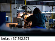Stepnogorsk, Kazakhstan April 04, 2012: Bearing production plant. Operator woman and control panel of CNC machine. Back view. Редакционное фото, фотограф Alexey Rezvykh / Фотобанк Лори