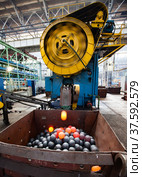 Stepnogorsk,Kazakhstan April 04, 2012: Bearing production plant workshop. Mechanic press for stamping steel balls. Red hot balls falling in metal hopper. Motion blurred of machine rotor and one ball. Редакционное фото, фотограф Alexey Rezvykh / Фотобанк Лори