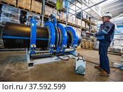 Stepnogorsk, Kazakhstan - April 04, 2012: Plastic pipes production plant. Engineer adjusting pipes joining equipment. Редакционное фото, фотограф Alexey Rezvykh / Фотобанк Лори
