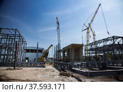 Mobile cranes and grey metal grating constructions and concrete support on blue sky. Assembling a new factory buildings. Abstract construction site picture. Стоковое фото, фотограф Alexey Rezvykh / Фотобанк Лори