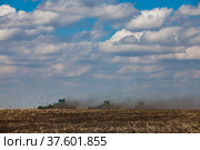 Tractors cultivating soil with plows. Spring sowing campaign. Dust cloud. Blue sky, nice clouds. Стоковое фото, фотограф Alexey Rezvykh / Фотобанк Лори