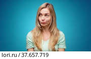 Thoughtful woman looking aside with pensive expression againast blue background. Стоковое видео, видеограф Сергей Толмачёв / Фотобанк Лори
