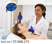 Hispanic woman beautician doing needle-free mesotherapy for young woman. Стоковое фото, фотограф Яков Филимонов / Фотобанк Лори