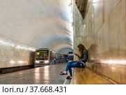 A young adult girl on the bench is waiting for a train at the metro station. (2019 год). Редакционное фото, фотограф Андрей Никитин / Фотобанк Лори