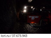 Khromtau, Aktobe region, Kazakhstan - May 06 2012: Gold mine underground gallery. Mining machine and engineers. Focus on people. Редакционное фото, фотограф Alexey Rezvykh / Фотобанк Лори
