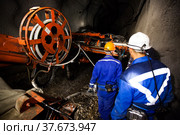 Khromtau, Aktobe region, Kazakhstan - May 06 2012: Gold mine underground gallery. Ore mining machine and engineers. Редакционное фото, фотограф Alexey Rezvykh / Фотобанк Лори