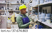 Cheerful Latino workman preparing for pipework routing, choosing supplies in shop of building materials. Стоковое видео, видеограф Яков Филимонов / Фотобанк Лори