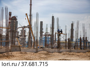 Aktau, Kazakhstan - May 19, 2012 Construction of modern asphaltic bitumen plant. Assembling building columns. Workers on forms and concrete pump hose. Focus on worker. Стоковое фото, фотограф Alexey Rezvykh / Фотобанк Лори